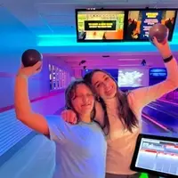 A mentor and their mentee are pictured, smiling, holding up small bowling balls and smiling.