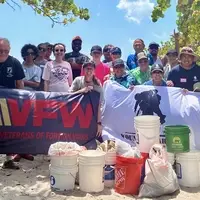Volunteers from REAL AMERICANS CORPORATION, VFW Post 1966, and Wounded Warrior Project gather after participating in a collaborative beach cleanup in South Florida.