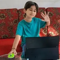 young latino boy smiling and waving hello during an online English class