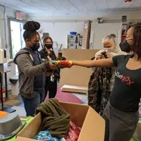 Director ellice handing a tie dye shirt to a student