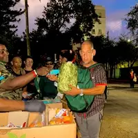 REAL AMERICANS CORPORATION volunteers distributing food and essential supplies to community members during an evening homeless outreach operation in Miami-Dade County, Florida.