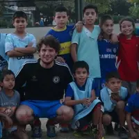 Volunteer with many children at football workshop