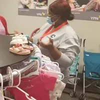 AmeriCorps Member in front of a clothing rack of children's clothes