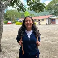 latina youth female standing her school's courtyard wearing backpack and smiling