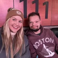 A mentor, pictured with long hair and wearing a beanie, with their mentee, wearing a light brown hoodie that says BOSTON.