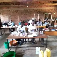 Students in a rural Ugandan classroom smiling and learning, representing TNYME Uganda’s mission to provide education and mentorship to disadvantaged youth. Volunteers can help set up and manage a GoFundMe campaign to raise funds for building a permanent school on 2 acres of land.