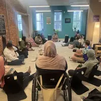 A group of men and women sitting in a circle on the floor