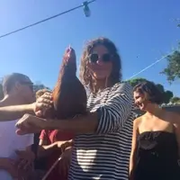 Man in sunglasses holding a chicken.