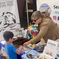 Gena, our ED, leading a hands-on activity with a young visitor at an outreach event