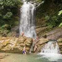 A group of Semillas Life volunteers cooling off and enjoying a large natural waterfall during a weekend excursion in the rainforest of Codo del Pozuzo, Peru. The image highlights the incredible biodiversity and natural beauty of the Amazonian landscape where the NGO operates.