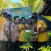 A diverse group of SERA2030 volunteers is actively participating in environmental activities at APAO Village in Kigamboni, Tanzania. Some volunteers are planting Moringa trees directly into the soil, digging small holes and placing seedlings with care, while others document surrounding biodiversity using mobile phones and cameras for scientific recording on iNaturalist. A few volunteers are seen walking around the landscape identifying plants, observing the natural environment, and taking detailed notes. The atmosphere is vibrant and collaborative, with sunlight filtering through nearby trees and open natural spaces creating a peaceful setting. The volunteers appear focused, engaged, and united by a shared purpose—to restore land, strengthen climate resilience, and contribute their energy to a community-led environmental mission. Their movements, teamwork, and dedication reflect the spirit and impact of the SERA2030 initiative.
