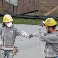 Man and woman in hard hats covered in dust bump fists