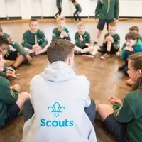 Male Cub Leader with young people sitting in a circle