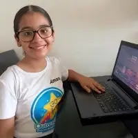 young student from Panama smiling at her computer wearing an Outreach360 t-shirt with her name, Amara on it
