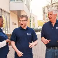 three VISTA members stand outside, engaged in dynamic conversation