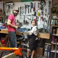 Bike shop manager Josh with a boy helping to fix bikes