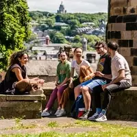 Students sitting on a wall with the city behind them