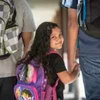 child with backpack looking backwards