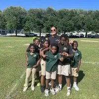 Our MAD PARK Community scholars standing together smiling with their volunteer youth coach after run club practice. Capturing the joy at the heart of our year-round movement programming and our commitment to empowering our youth through sport, mentorship, and community in Charleston, SC.