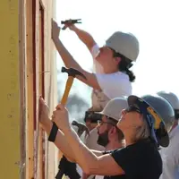 Volunteers hammering nails into wall