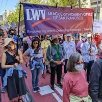 LWVSF members march on Market Street in San Francisco under a banner.