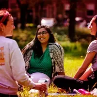 Students outside in park sitting on grass, talking