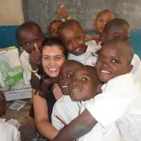 Children smiling around a volunteer in a classroom