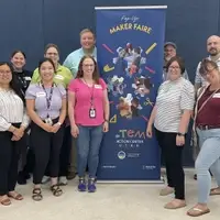 Group of volunteers in front of Pop Up Maker Faire sign.