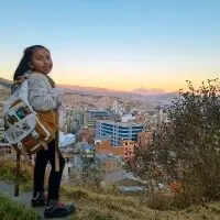 young female Bolivian student with backpack looking over her city on a hill