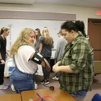 One medical occupations student takes another student's blood pressure.