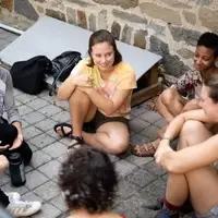 Small Group conversation with 5 people sitting on the ground at QVS National Orientation.