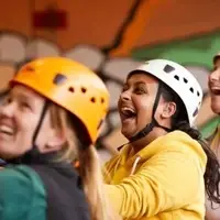 Rock climbing fun with three people with safety gear by a wall