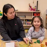 a teacher plays with a preschooler at a table