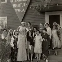 black and white photo of women from various cultures in front of a sign reading "International Institute YWCA"