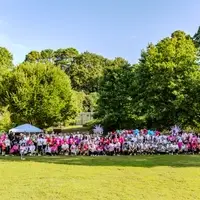 Group shot of race participants on grass field dressed in all different colors to include pink, white, blue, and grey.