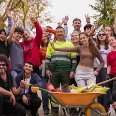 Personas voluntarias posando con una carretilla con materiales