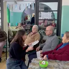Una chica leyendo cartas a unas personas mayores