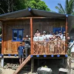 Personas voluntarias frente a la casa construida