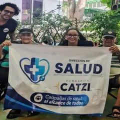 Beneficiarios y voluntarios sujetando un banderín de fundación CATZI y la Dirección de Salud