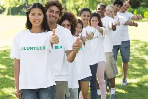 A group of people smiling with their thumbs up.
