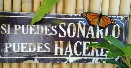 Una mariposa monarca posada sobre un cartel que dice "Si puedes soñarlo, puedes hacerlo"