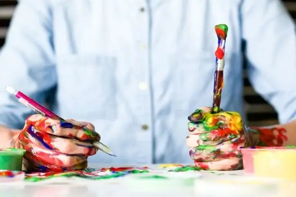 Unas manos llenas de pintura de varios colores