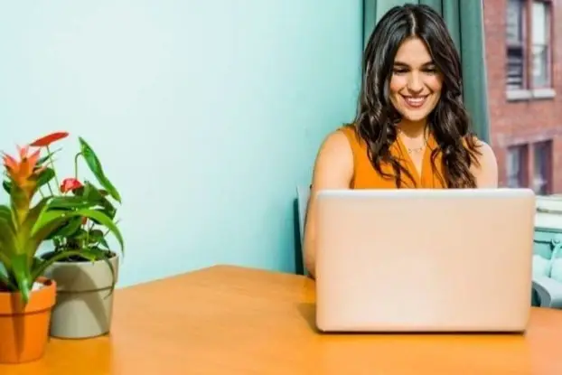 Mujer sonreída trabaja frente a computador