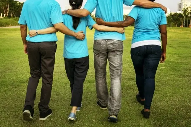 Foto desde atrás de cuatro jóvenes abrazados