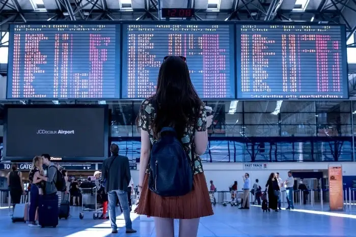 A woman watches the train schedule in the train station.