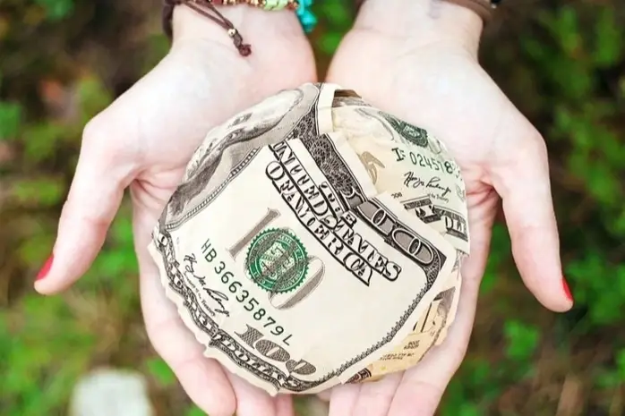 Unas manos sosteniendo una bola de billetes