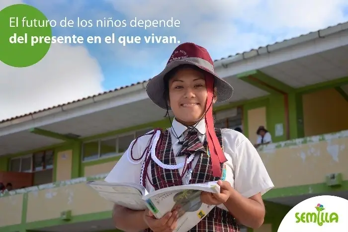 Una niña del proyecto Semilla con uniforme leyendo