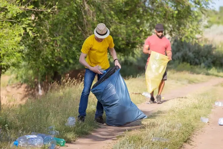 Two men collecting litter in trash bags as a part of their volunteer efforts