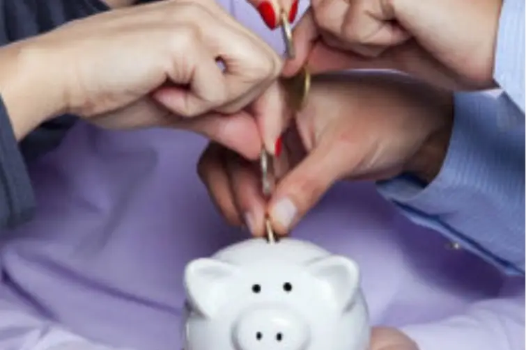 Varias manos poniendo monedas en una alcancía