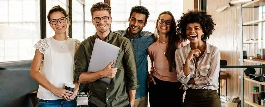 A group of people smiling and posing in an office.